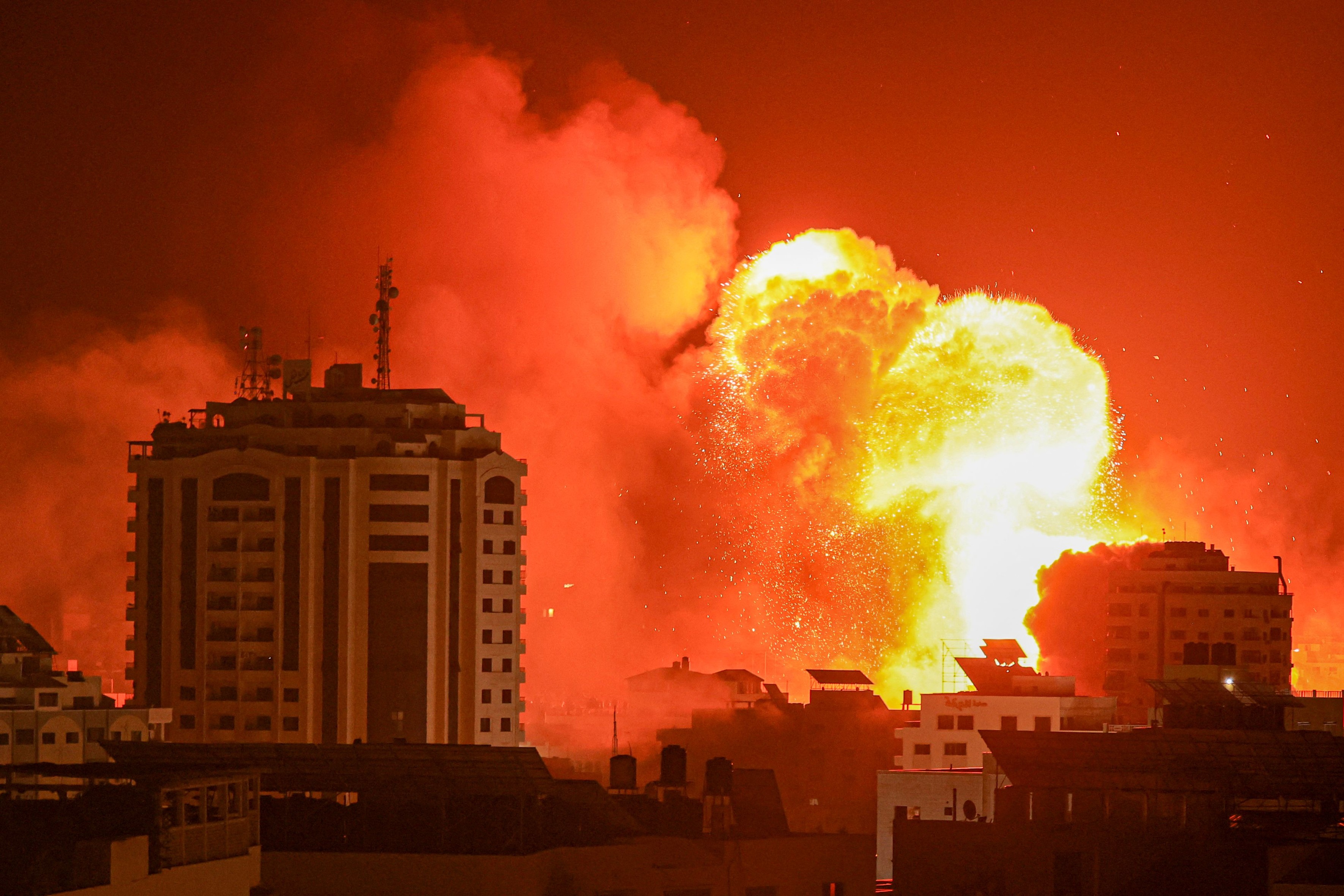Das Bild zeigt mehrere Gebäude bei Nacht sowie ein großer Feuerball, der durch eine Explosion entstanden ist.