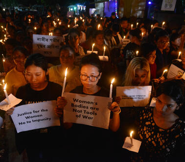 Frauen mit Kerzen halten Plakate hoch, auf denen Frauenrechte eingefordert werden.