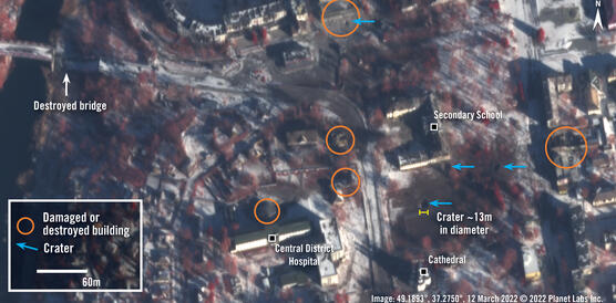 Das Bild zeigt ein Satellitenbild einer Stadt, darauf zu sehen sind orangene Kreise und blaue Pfeile, die Gebäude kennzeichnen, die durch Angriffe zerstört wurden