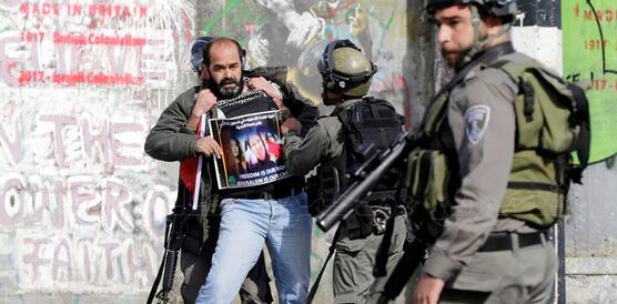 Das Bild zeigt Sicherheitskräfte mit Waffen, wie sie einen Mann festhalten