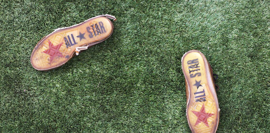 Die Sohlen von Converse All-Star-Schuhen auf einem Kunstrasen.