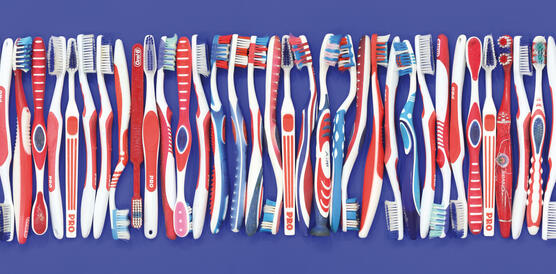 Viele Zahnbürsten in einer Reihe nebeneinander dicht an dicht gelegt.