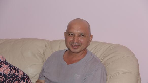 Erkin Musaev sitzt lächelnd auf einem Sofa