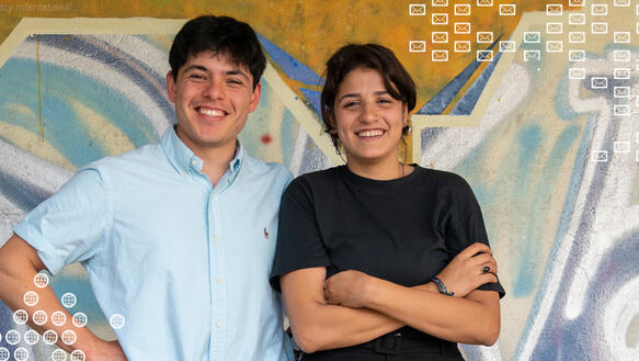 Porträt von zwei jungen Menschen. Im Hintergrund ist eine bunte Wand mit Graffiti.