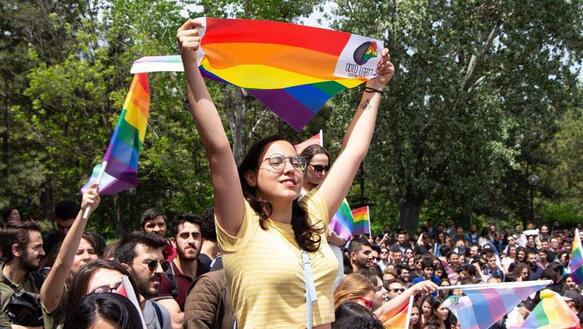 Junge Frau hält Regenbogenflagge bei Demo