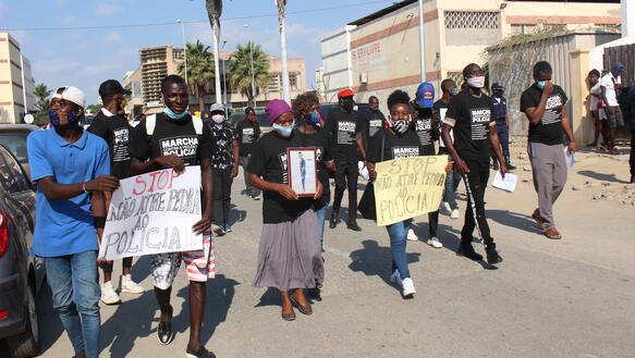 Menschen mit Gesichtsmasken (aufgrund von Covid-19) demonstrieren, sie halten Schilder gegen Polizeigewalt, eine Frau hält das Foto eines getöteten Jugendlichen