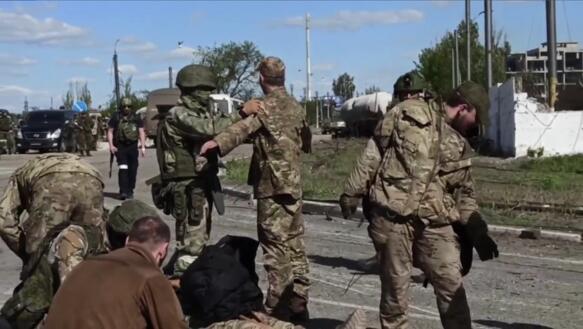 Bewaffnete russischen Soldaten durchsuchen auf einer Straße unbewaffente ukrainische Soldaten, die sich ergeben haben.