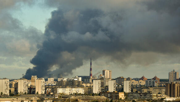 Das Bild zeigt mehrere Hochhäuser einer Stadt, über der eine Rauchwolke liegt.