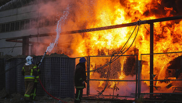 Das Bild zeigt wie ein Gebäude brennt, Feuerwehrkräfte versuchen den Brand zu löschen