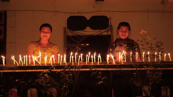 Das Bild zeigt zwei Frauen, die Kerzen anzünden