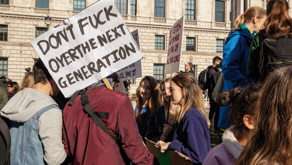 Schüler halten Schilder vor dem Gebäude des britischen Parlaments in der Hand und protestieren.
